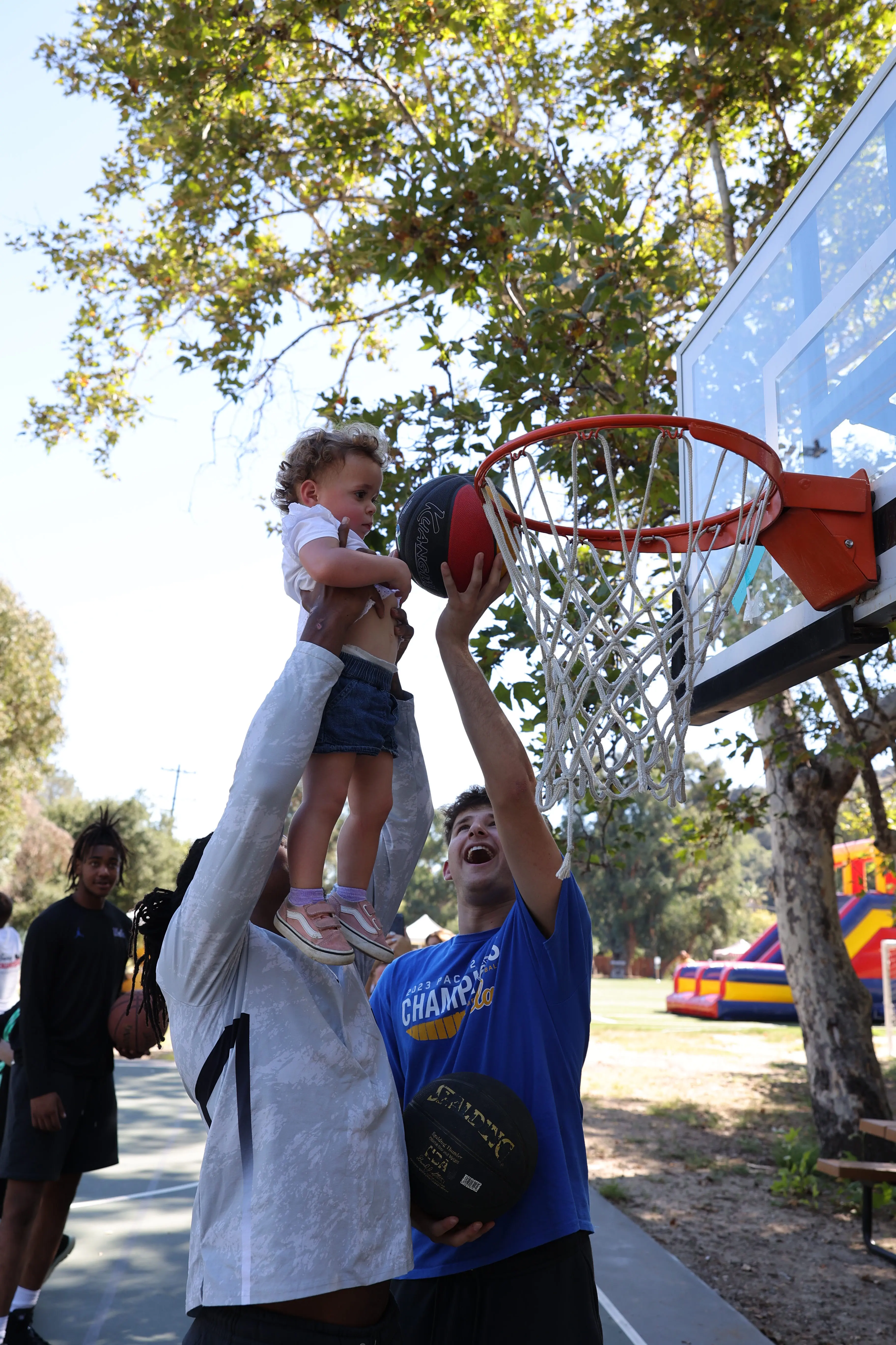Person lifting toddler up to dunk