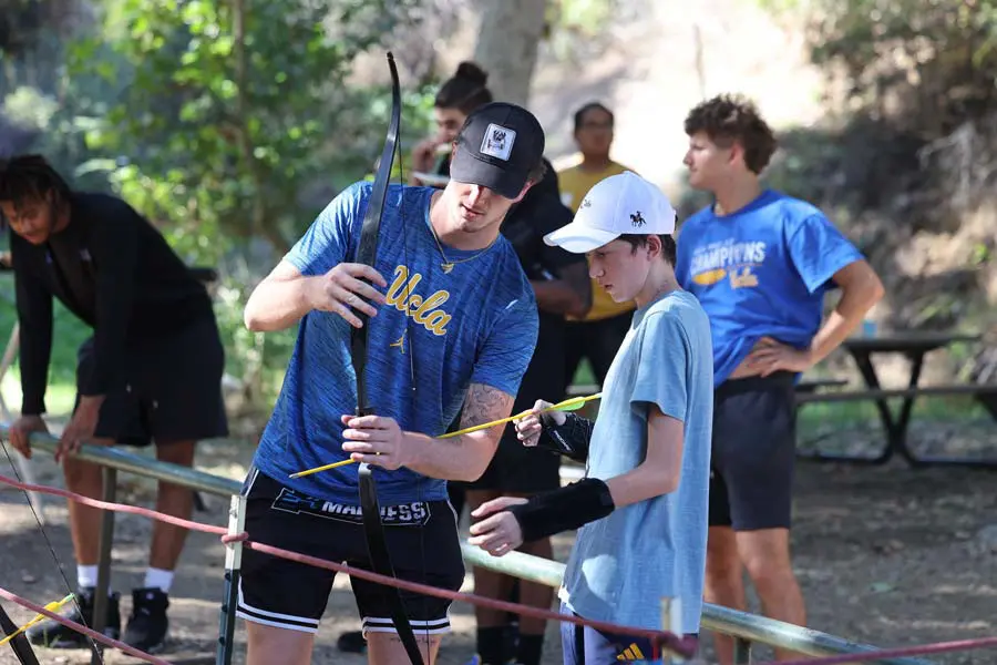 Student-athlete showing participant how to use bow